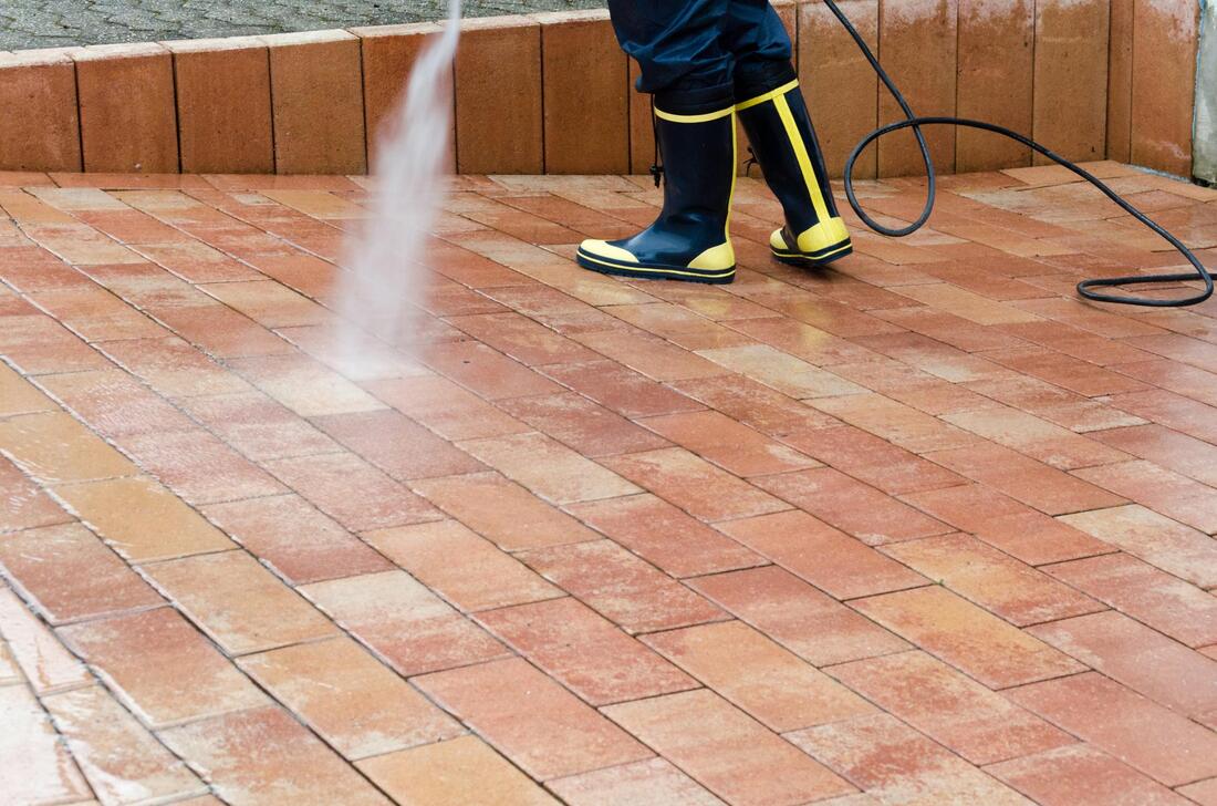 worker in boots spraying the tile